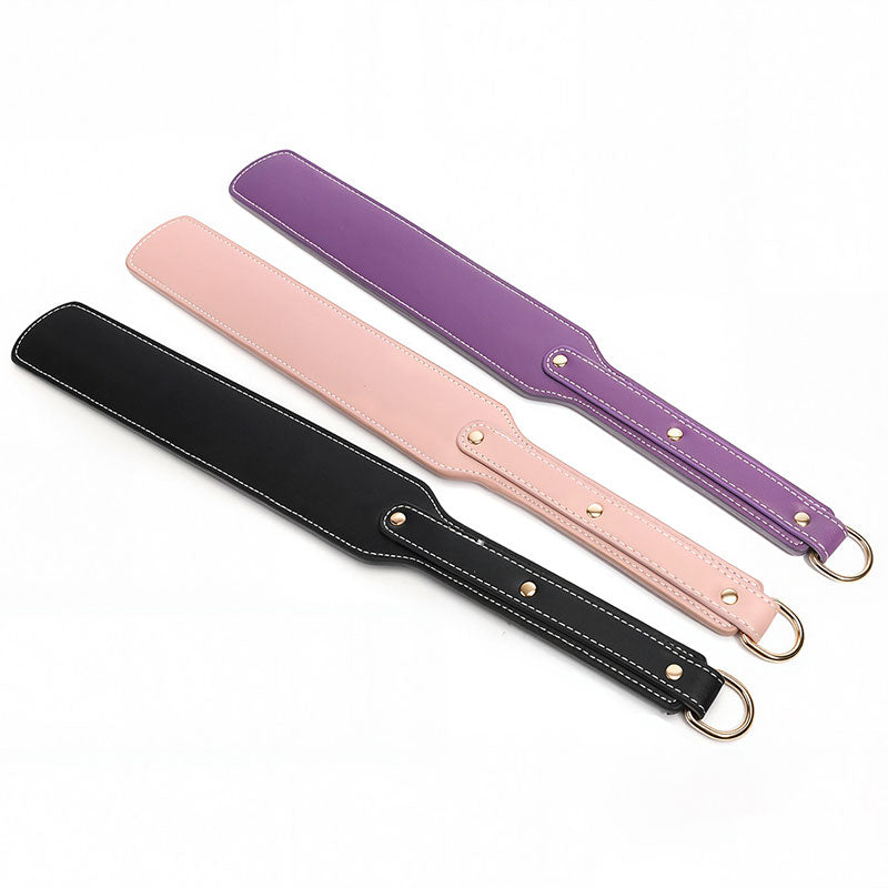 Wondebliss faux leather spanking paddle in black, pink and purple, three color options displayed together